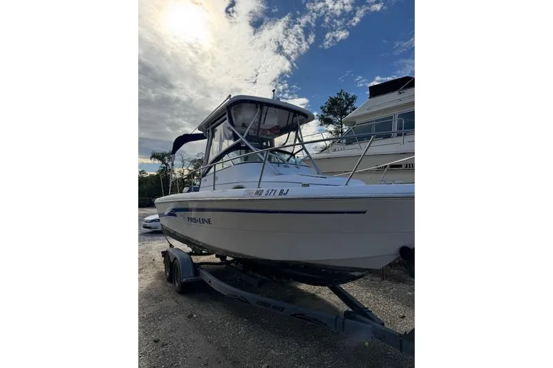 Slide: The Image of 1999 Pro-Line 24 Walkaround boat on trailer under cloudy sky. - 5