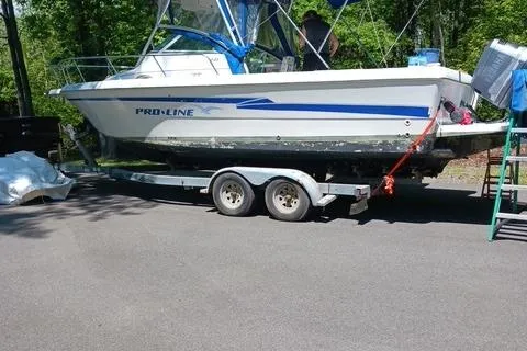 Slide: The Image of 1999 Pro-Line 24 Walkaround boat on trailer, parked outdoors on sunny day. - 6