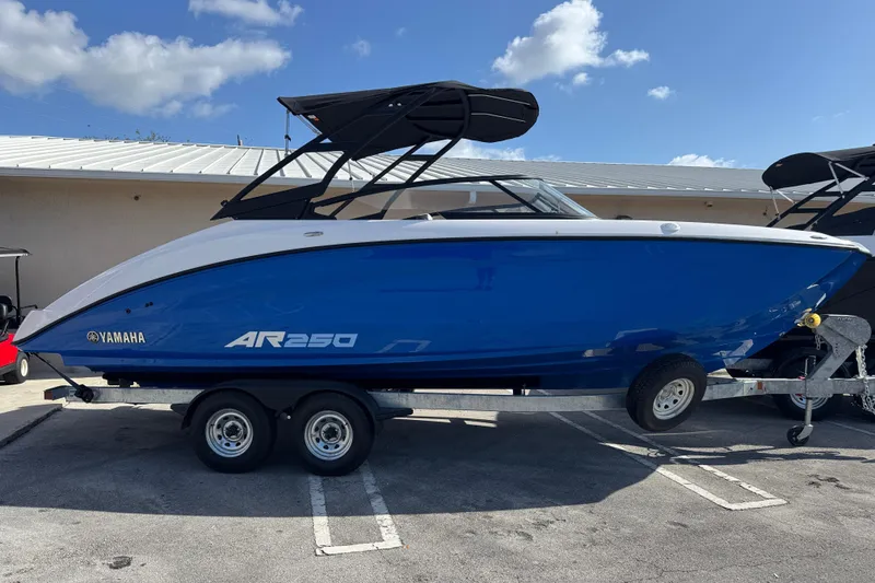 The Image of 2025 Yamaha Boats AR250 in blue on trailer under clear sky. - 1