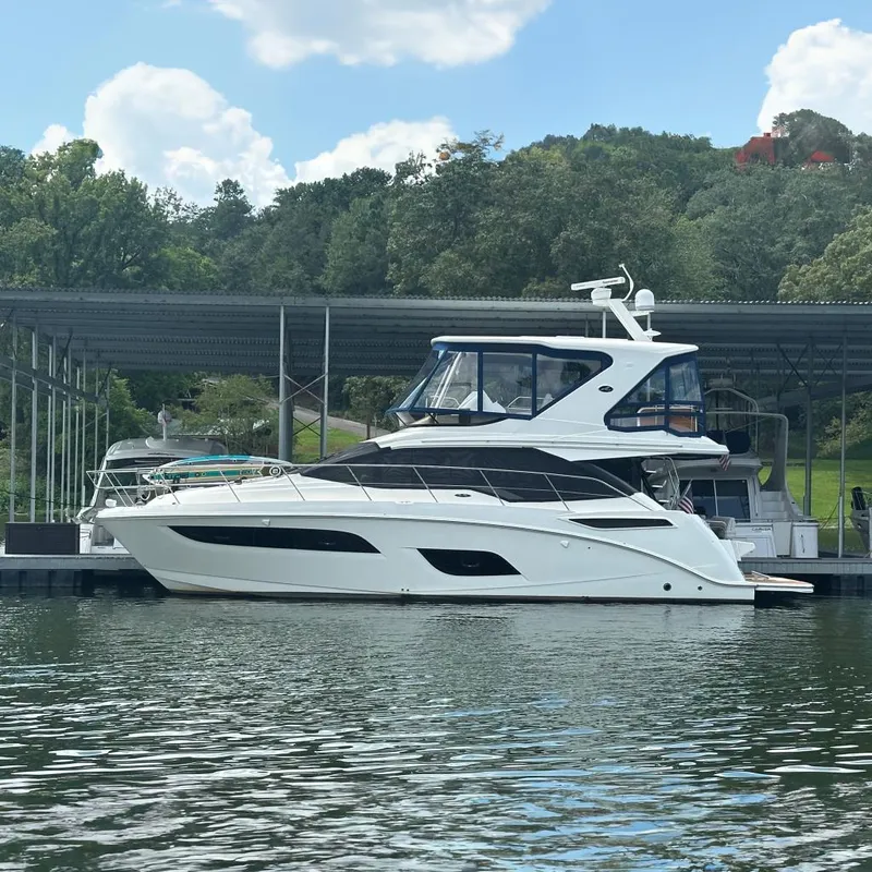 The Image of 2017 Sea Ray Fly 460 yacht docked at marina, surrounded by lush greenery. - 0