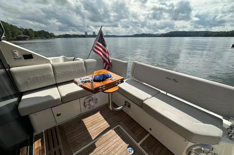 Slide: The Image of 2017 Sea Ray Fly 460 yacht interior with seating, table, and American flag on a serene lake. - 13
