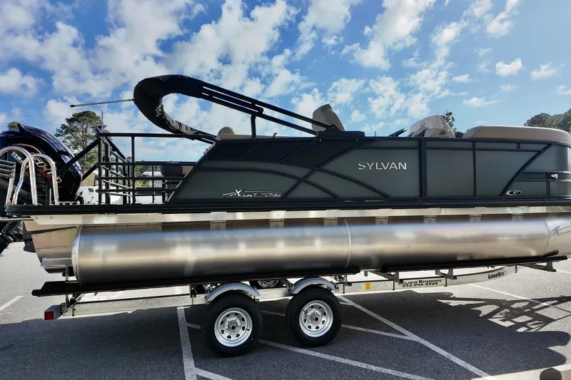 Slide: The Image of 2026 Sylvan Mirage X3 CLZ pontoon boat on trailer under blue sky. - 13