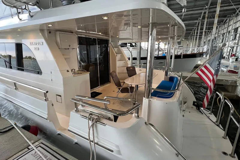 Slide: The Image of Luxurious 2012 Hampton motor yacht docked, featuring elegant outdoor seating and American flag. - 3