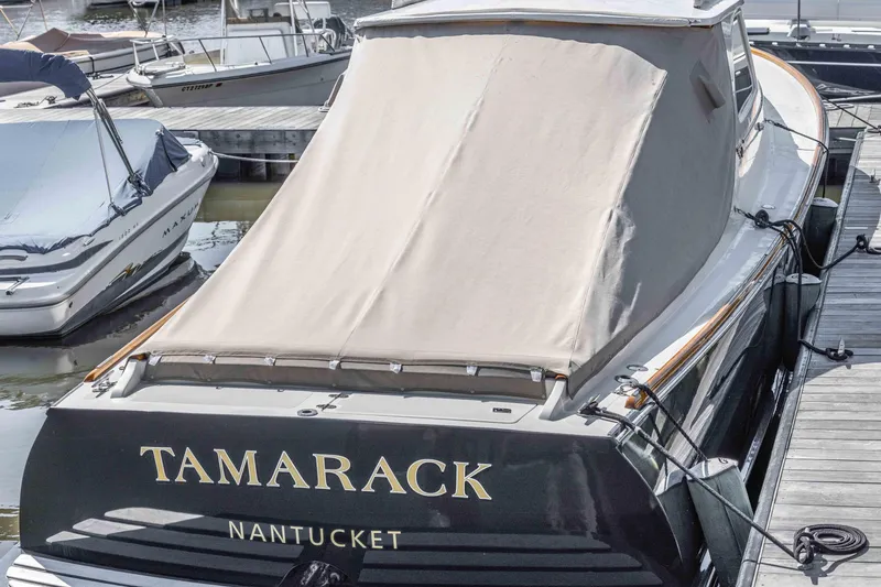Slide: The Image of 1999 Hinckley Picnic Boat 36 Classic docked, covered, with "Tamarack" and "Nantucket" on the stern. - 26