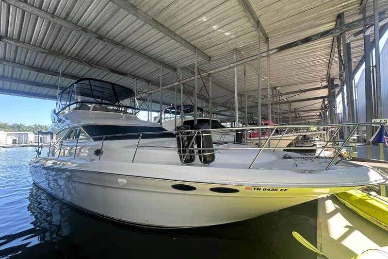 The Image of 2000 Sea Ray 400 Sedan Bridge yacht docked at a marina under cloudy skies. - 0