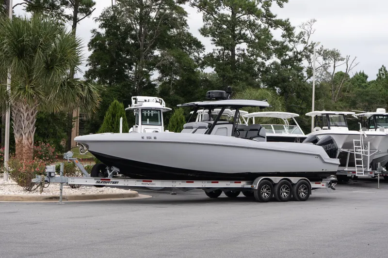 The Image of 2024 Sunsation 32 CCX boat on trailer, parked outdoors with trees in background. - 1