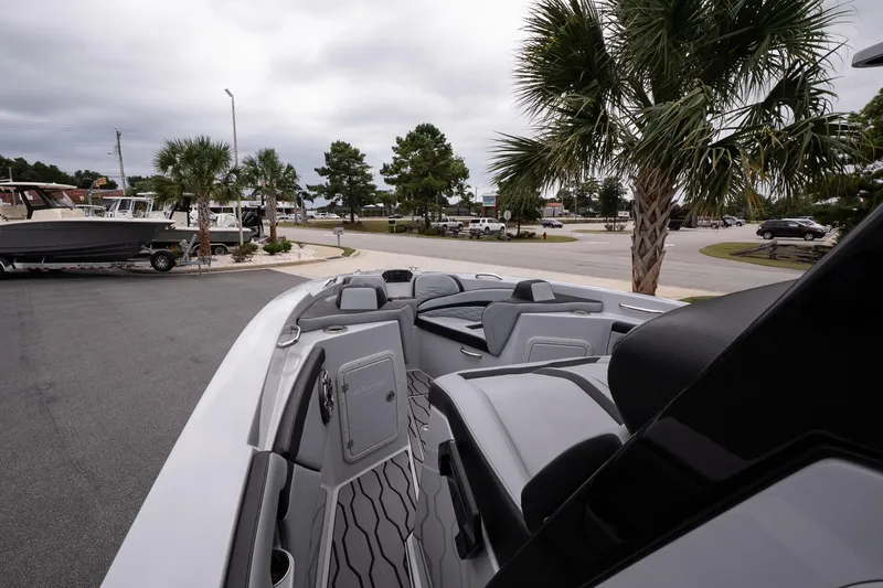 Slide: The Image of 2024 Sunsation 32 CCX boat interior with sleek seating, parked near palm trees. - 14