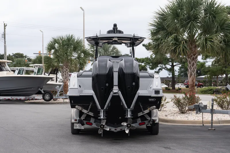 Slide: The Image of 2024 Sunsation 32 CCX boat on trailer, rear view with dual engines, palm trees in background. - 6