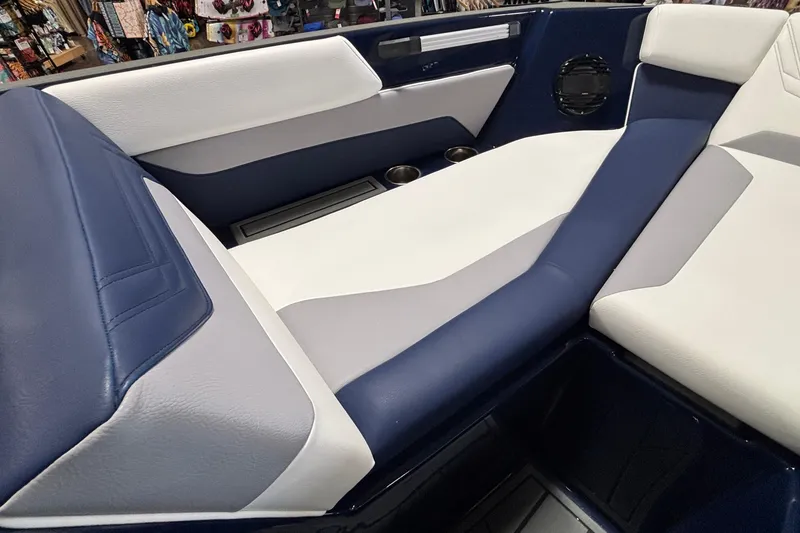 Slide: The Image of 2026 ATX Surf Boats 24 Type-S interior with blue and white seating, cup holders, and speaker. - 13
