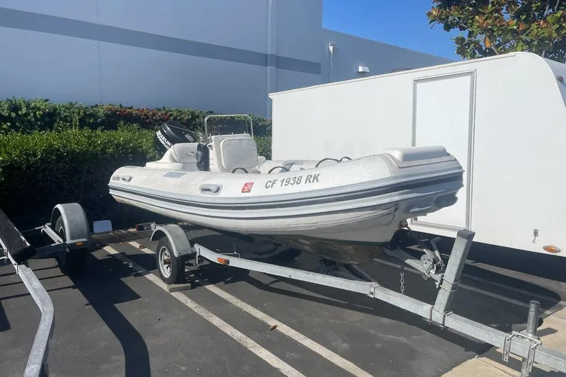 The Image of 2006 Caribe CL 14 RIB boat on trailer in parking lot. - 1