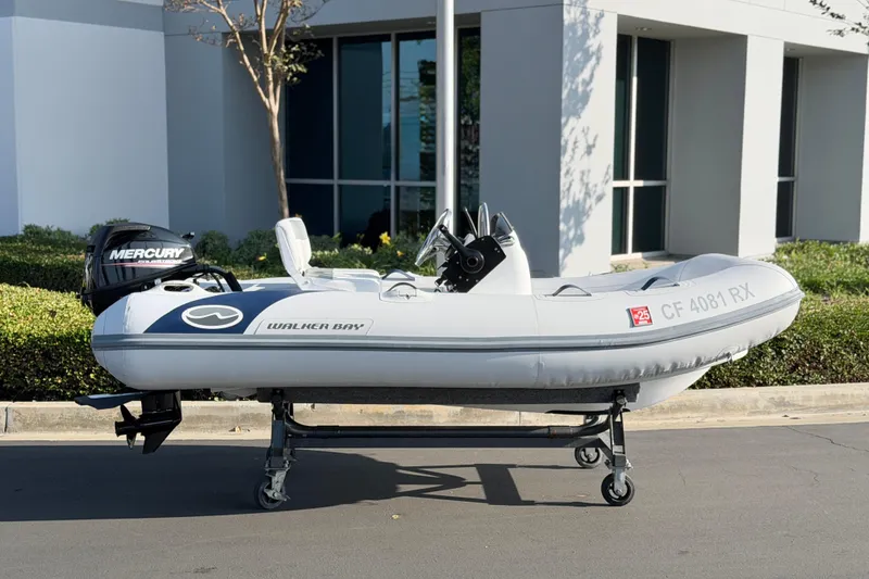 Slide: The Image of 2015 Walker Bay Genisis 310 inflatable boat with Mercury outboard motor on a wheeled stand. - 13