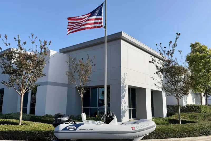 Slide: The Image of 2015 Walker Bay Genisis 310 boat parked outside modern building with American flag. - 14