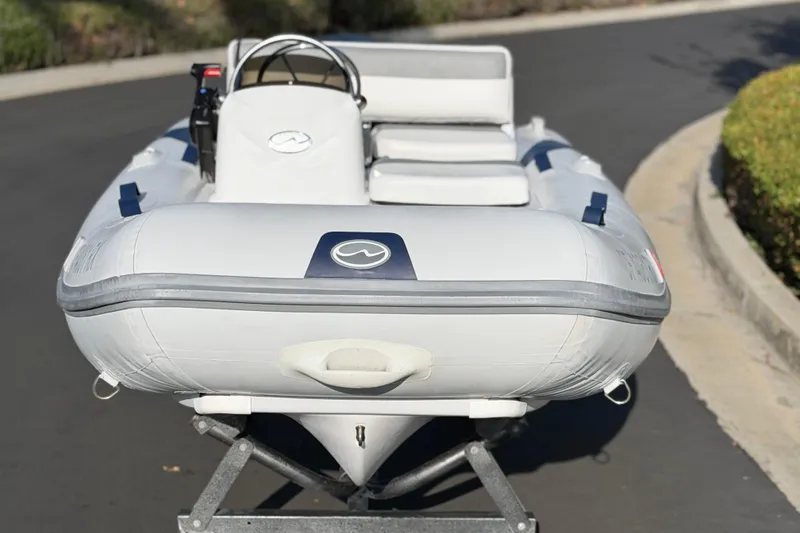 Slide: The Image of 2015 Walker Bay Genisis 310 inflatable boat on a trailer, parked on a road. - 18