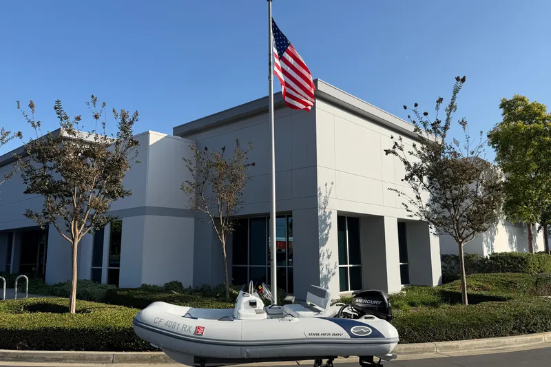 Slide: The Image of 2015 Walker Bay Genisis 310 boat parked outside modern building with American flag. - 6