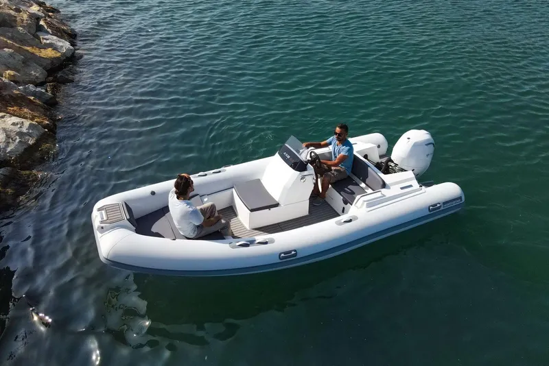 Slide: The Image of 2026 Northstar AXIS 5.3 boat on water with two people onboard, near rocky shore. - 2