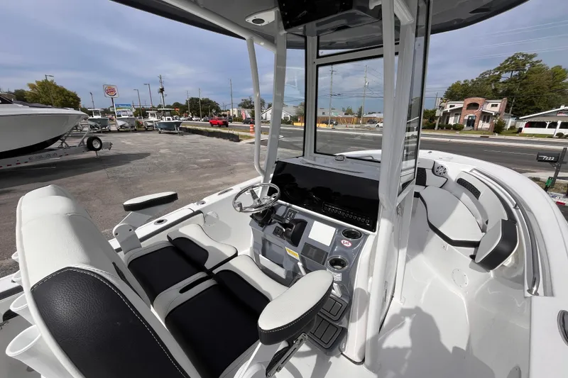 Slide: The Image of 2026 Tidewater 220 LXF boat interior with modern helm and seating, parked outdoors. - 14