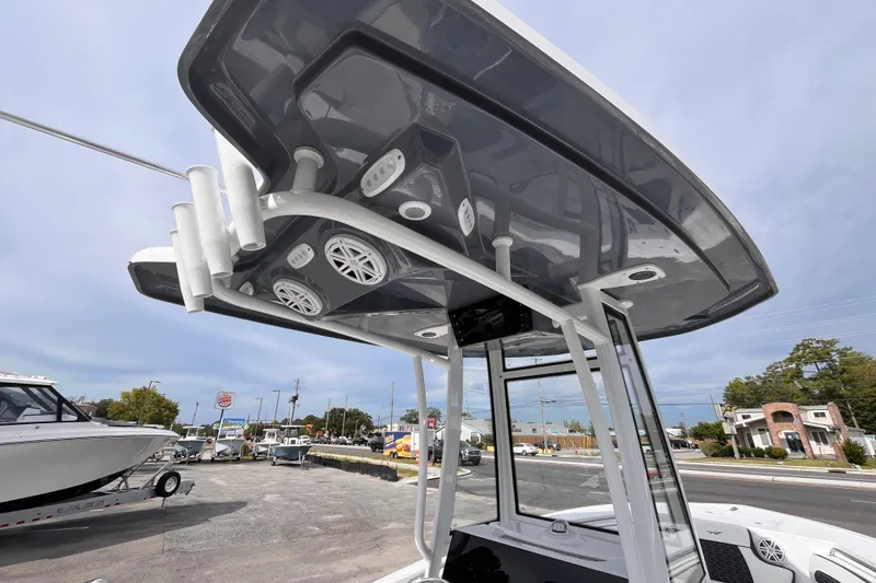 Slide: The Image of 2026 Tidewater 220 LXF boat with modern T-top and speakers, parked outdoors. - 16