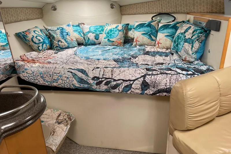 Slide: The Image of 2001 Larson Cabrio 330 cabin with nautical-themed bedding and cozy seating area. - 6