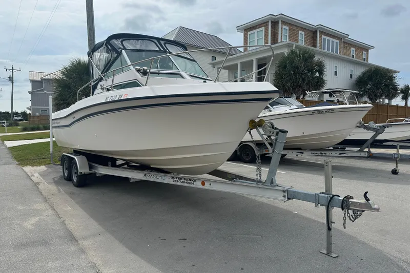 Slide: The Image of 1987 Grady-White Gulfstream 232 boat on trailer, parked near coastal homes. - 2