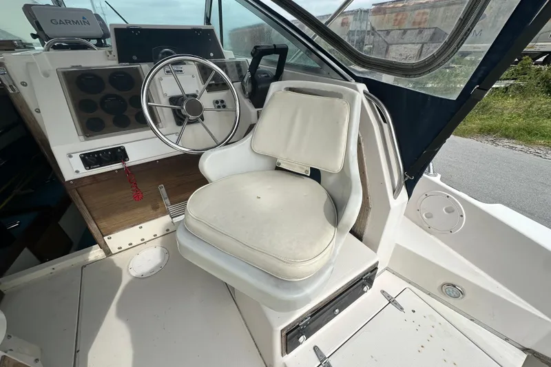 Slide: The Image of 1987 Grady-White Gulfstream 232 boat cockpit with steering wheel and cushioned seat. - 26