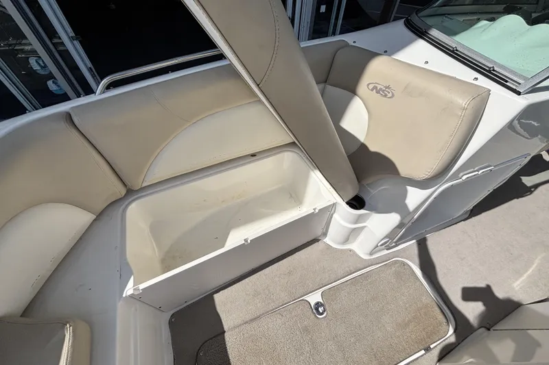 Slide: The Image of 2015 NauticStar 223 DC boat interior with beige seating and storage compartment. - 28
