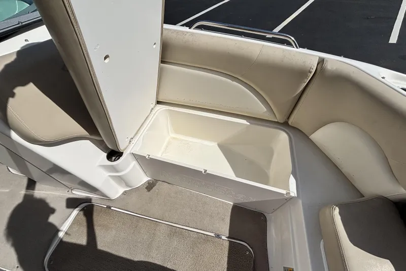 Slide: The Image of 2015 NauticStar 223 DC boat interior with open storage compartment and beige seating. - 29