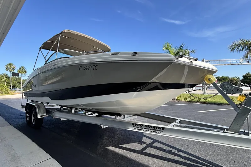 Slide: The Image of 2015 NauticStar 223 DC boat on trailer, parked outdoors under clear blue sky. - 3