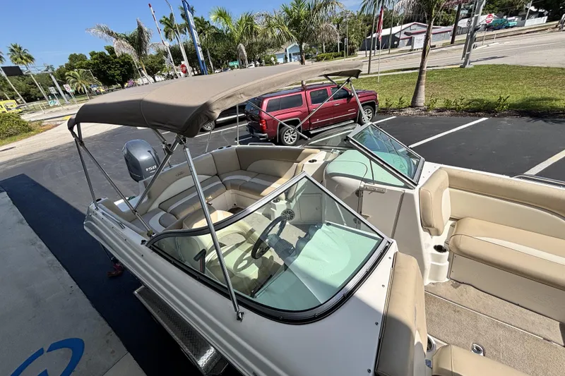 Slide: The Image of 2015 NauticStar 223 DC boat with canopy, parked near palm trees and a red SUV. - 35