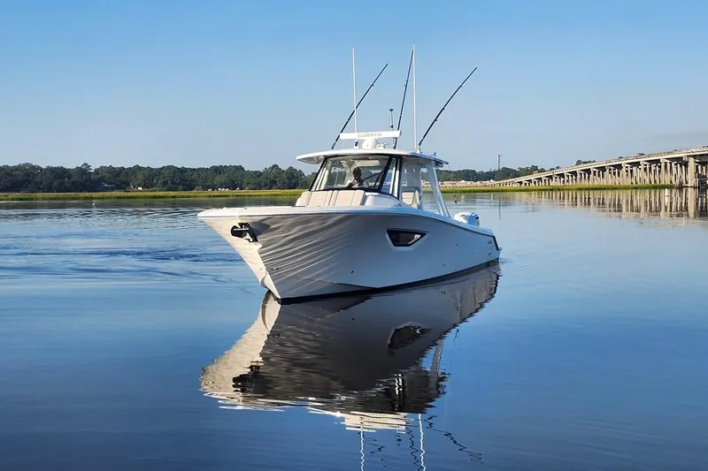 Slide: The Image of 2023 Pursuit S 378 Sport boat on calm water near a bridge. - 12