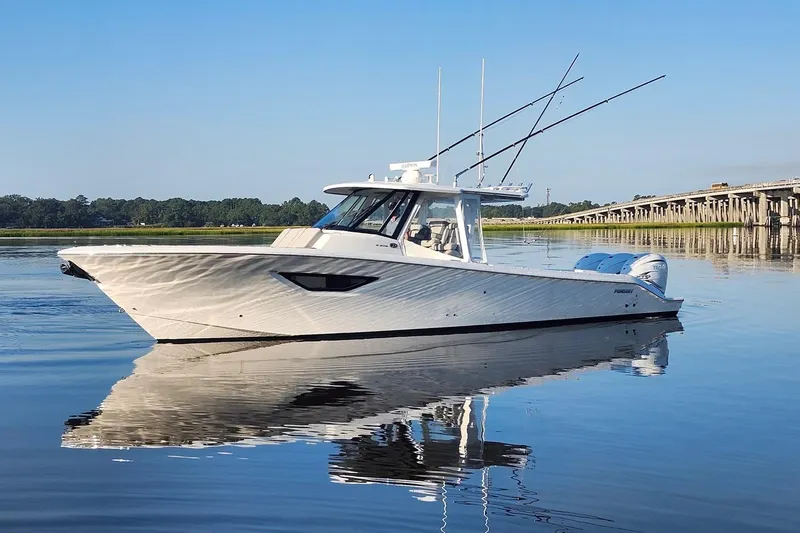 Slide: The Image of 2023 Pursuit S 378 Sport boat on calm water near a bridge, clear blue sky. - 16