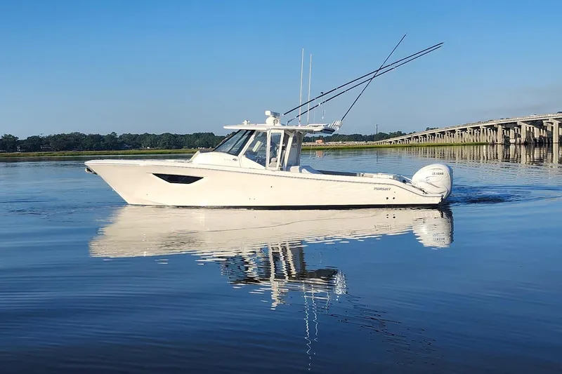 Slide: The Image of 2023 Pursuit S 378 Sport boat on calm water, reflecting bridge and clear sky. - 19