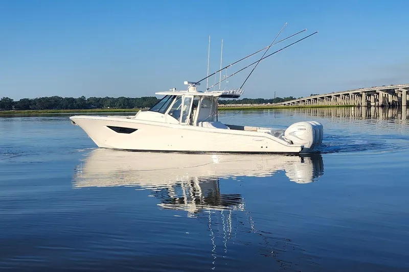 Slide: The Image of 2023 Pursuit S 378 Sport boat on calm water near a bridge. - 20