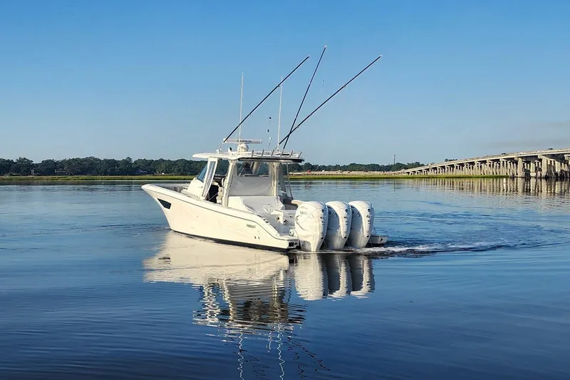Slide: The Image of 2023 Pursuit S 378 Sport boat cruising on calm water near a bridge. - 23
