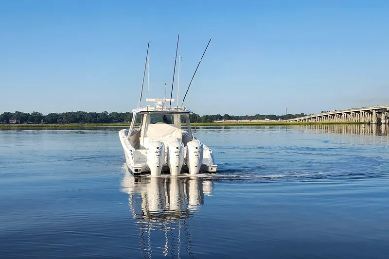 Slide: The Image of 2023 Pursuit S 378 Sport boat cruising on calm water near a bridge. - 25