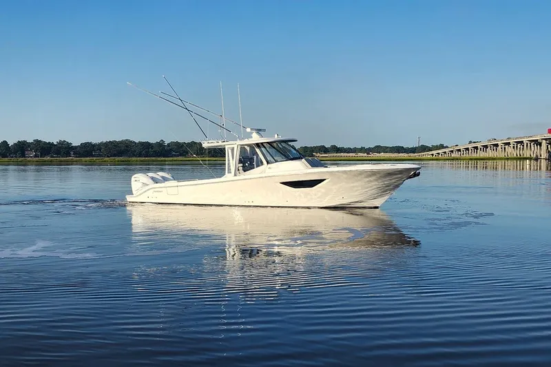 Slide: The Image of 2023 Pursuit S 378 Sport boat cruising on calm water near a bridge. - 33