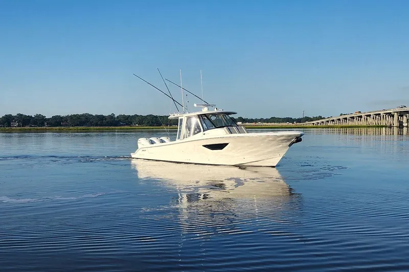 Slide: The Image of 2023 Pursuit S 378 Sport boat cruising on calm water near a bridge. - 35