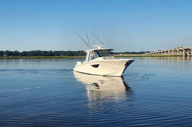 Slide: The Image of 2023 Pursuit S 378 Sport boat on calm water near a bridge. - 37