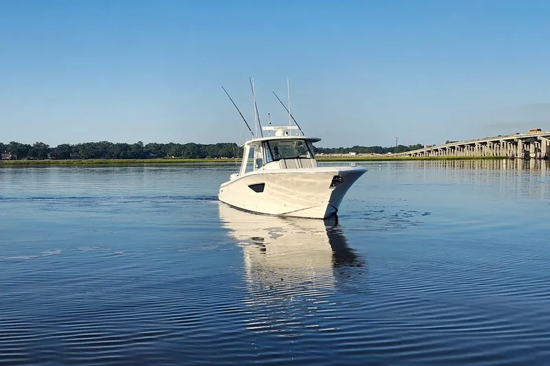 Slide: The Image of 2023 Pursuit S 378 Sport boat cruising on calm water near a bridge. - 38