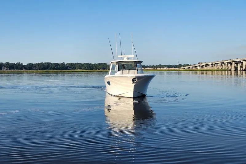 Slide: The Image of 2023 Pursuit S 378 Sport boat on calm water near a bridge. - 39