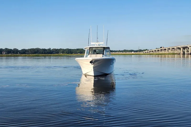 Slide: The Image of 2023 Pursuit S 378 Sport boat on calm water near a bridge. - 40