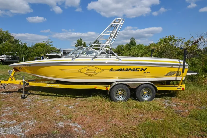 Slide: The Image of 2004 Supra Launch SS boat in vibrant yellow on a trailer, set against a clear sky. - 0