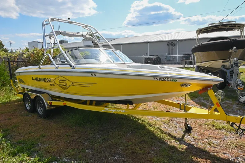 Slide: The Image of Yellow 2004 Supra Launch SS boat on trailer, parked outdoors under a sunny sky. - 2