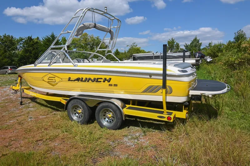 Slide: The Image of 2004 Supra Launch SS boat on trailer, yellow and white design, parked on grassy area. - 3