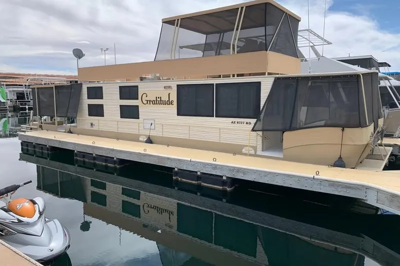 Slide: The Image of 1985 Boatel Hercules Custom houseboat docked, featuring beige exterior and screened windows. - 6
