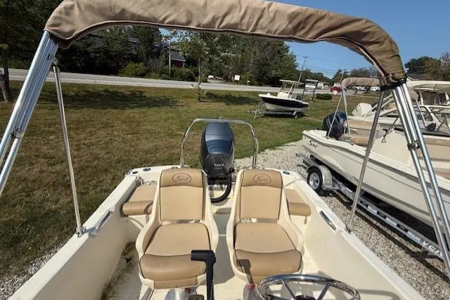 Slide: The Image of 2016 Scout 175 Sportfish boat with dual seats and canopy, parked on grass. - 2