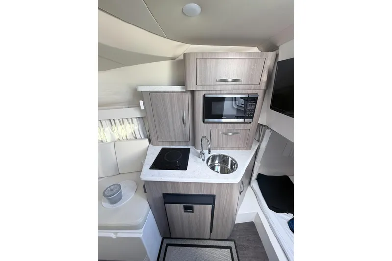 Slide: The Image of 2019 Regal 28 Express boat interior with kitchenette, featuring microwave, sink, and stove. - 21