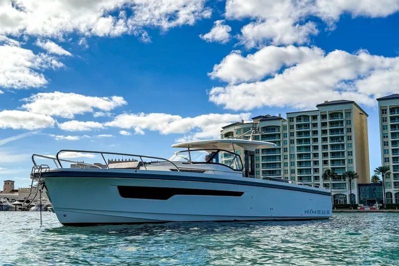 Slide: The Image of 2023 Nimbus Tender 11 yacht in marina, with modern buildings and blue sky background. - 1