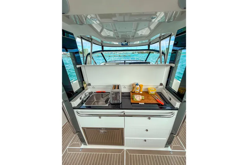 Slide: The Image of 2023 Nimbus Tender 11 boat kitchen with sink, toaster, and cutting board on deck. - 10