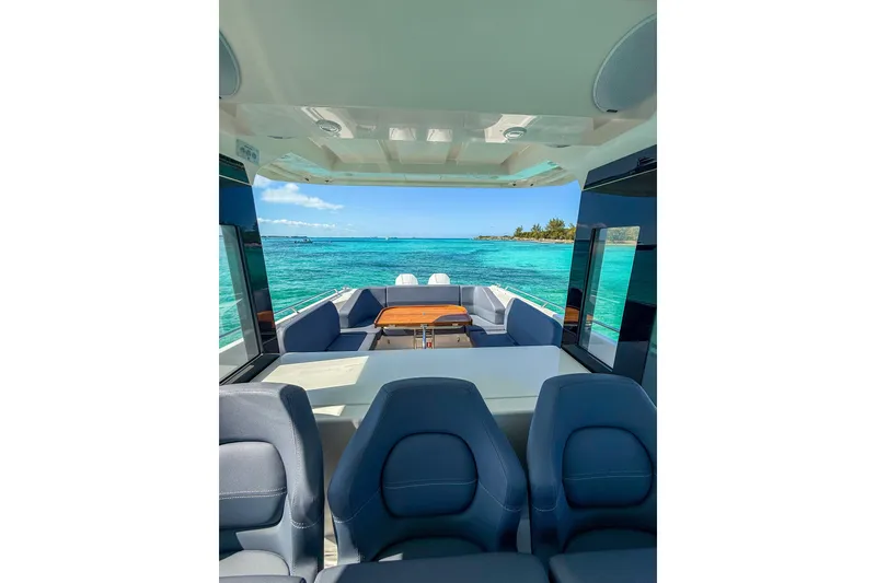 Slide: The Image of 2023 Nimbus Tender 11 interior with ocean view, featuring comfortable seating and a wooden table. - 11