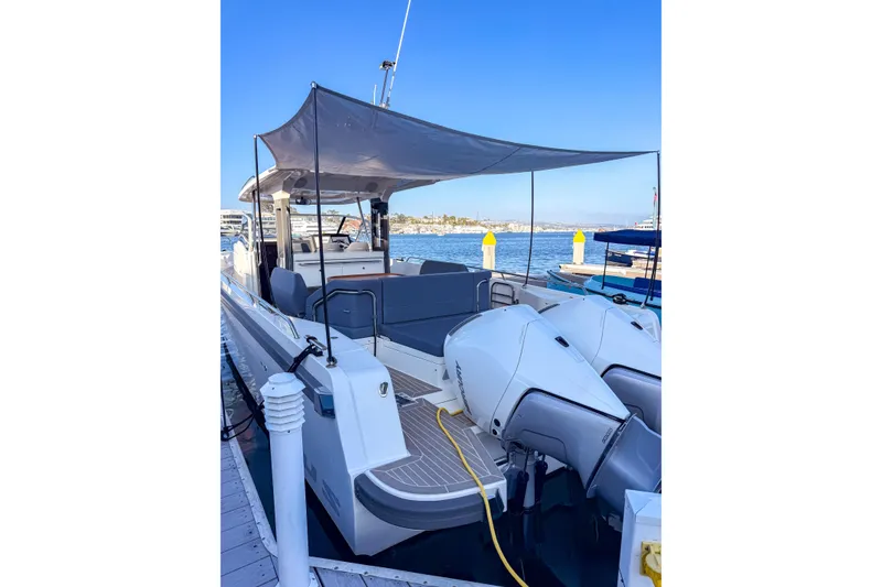 Slide: The Image of 2023 Nimbus Tender 11 boat docked, featuring dual engines and a shaded seating area. - 17